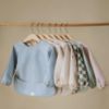 Picture of mushie Long Sleeve Baby Bib | Mess Free & Waterproof Fabric for Toddlers | Adjustable Fit for Ages 6-24 Months (Dinos)